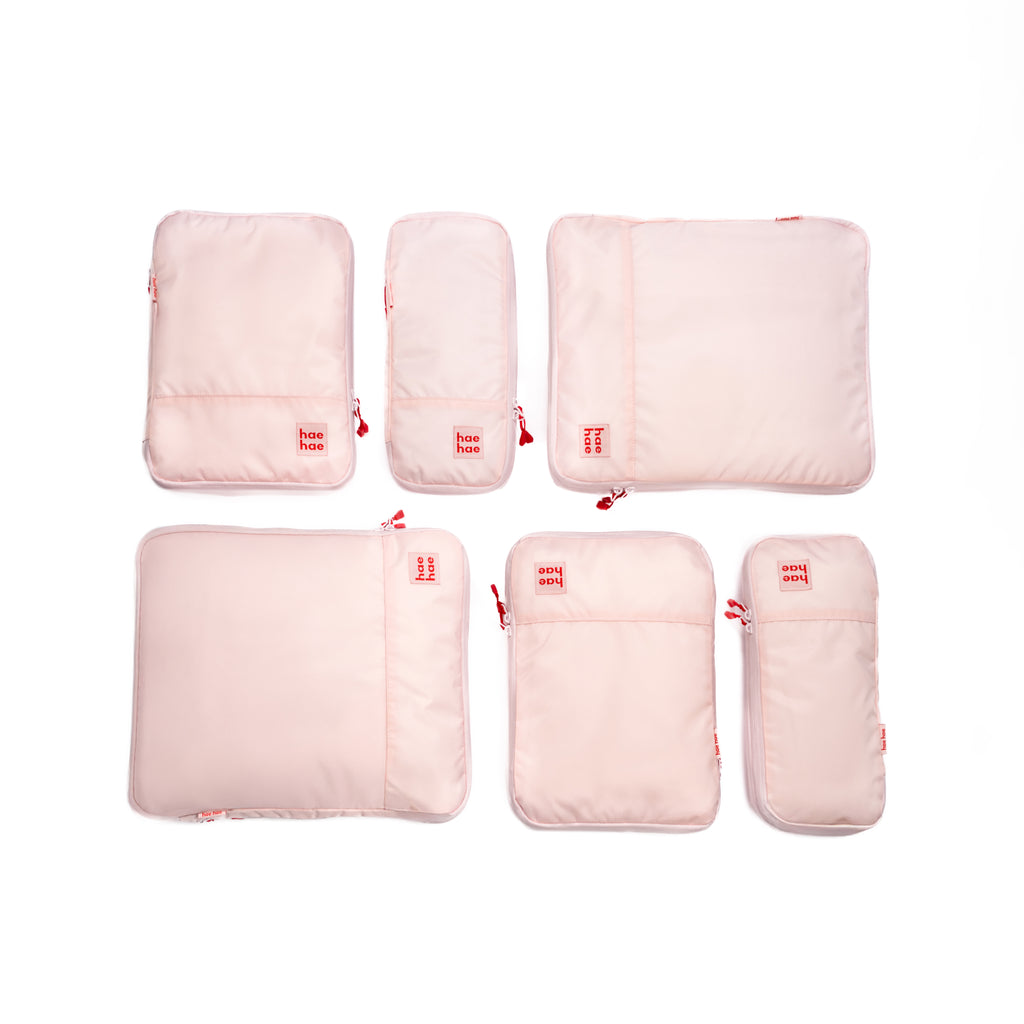 Set of pink travel packing cubes with visible brand logo on a white background
