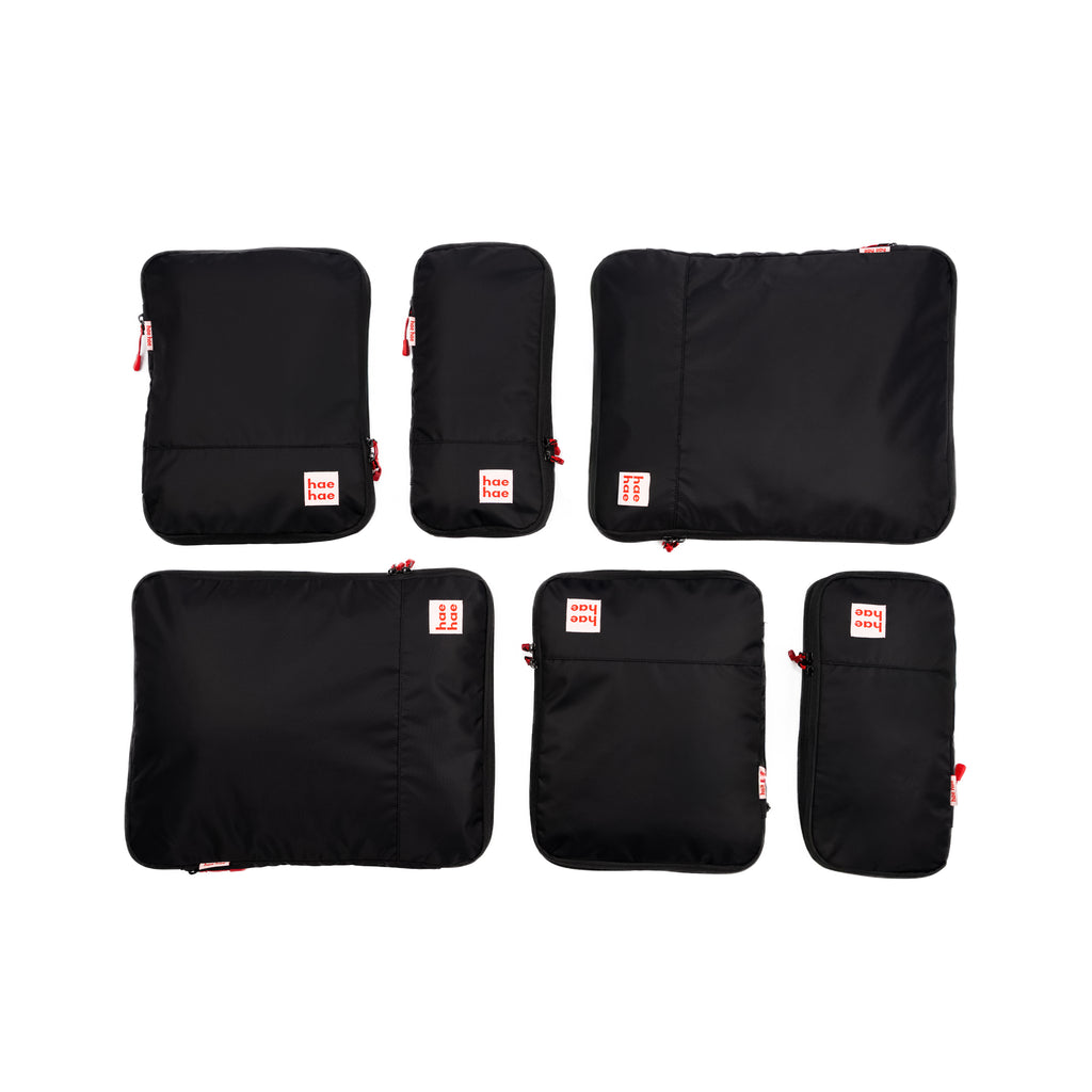 Set of black packing cubes with red labels on a white background
