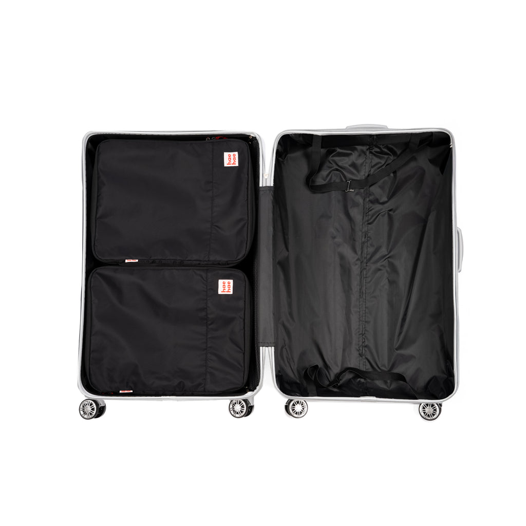 Two large compression packing cubes in silver open suitcase on a white background