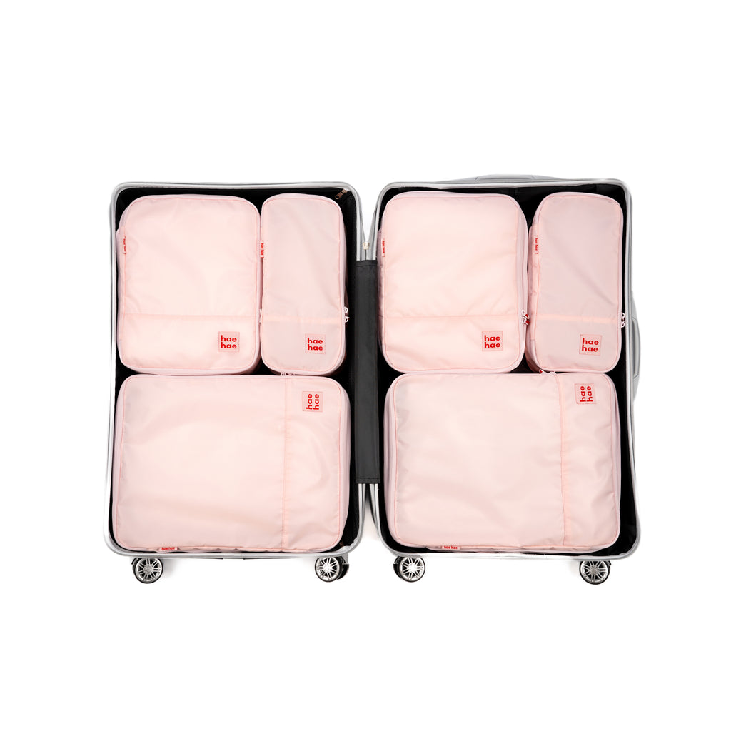 6 Pink packing cubes in an open suitcase on a white background, hae hae