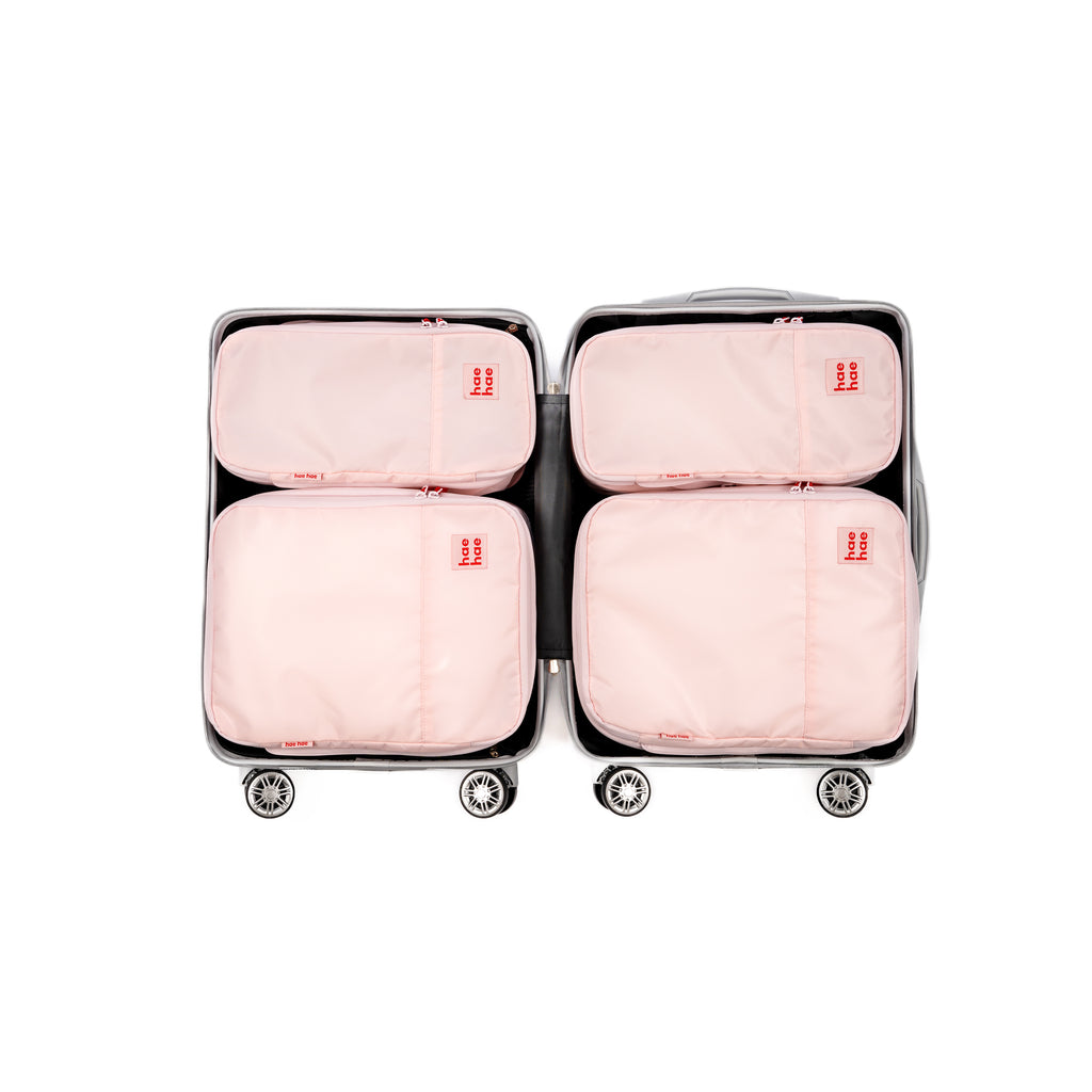 4 pack pink travel compression packing cubes within a suitcase on a white background
